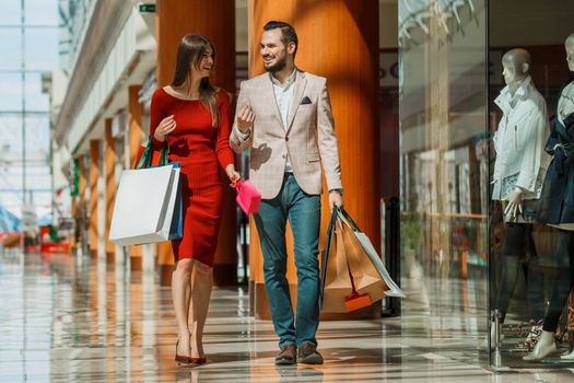 Happy beautiful young couple with shopping bags in mall