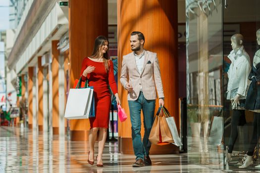 Happy beautiful young couple with shopping bags in mall