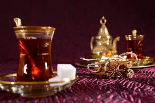Closeup of Turkish tea in traditional glass with star anise and cinnamon sticks