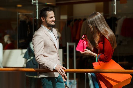 Happy beautiful young couple with gift in shopping mall