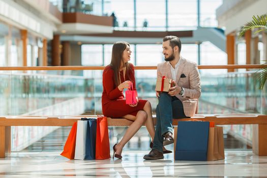 Happy beautiful young couple with shopping bags in mall