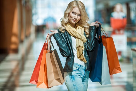 Sale and people - smiling woman with colorful shopping bags over supermarket background