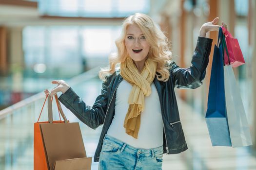 Sale and people - smiling woman with colorful shopping bags over supermarket background