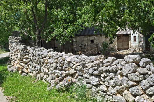 Stone fence and rustic old abandoned house