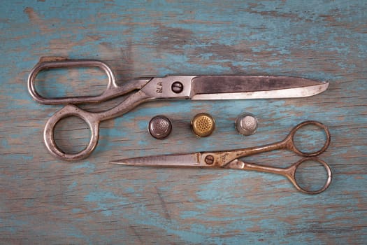 Retro sewing accessories - scissors and thimbles on blue wooden background