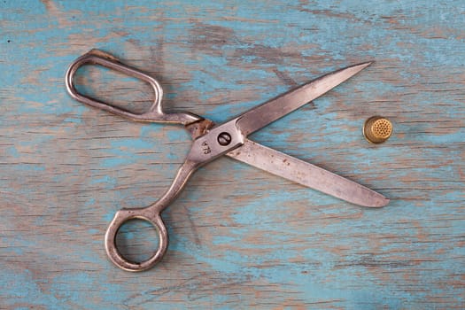 Retro sewing accessories - scissors and thimbles on blue wooden background