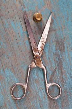 Retro sewing accessories - scissors and thimbles on blue wooden background