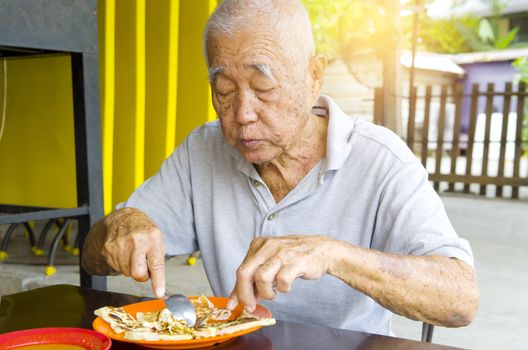 asian senior man having roti canai outdoor