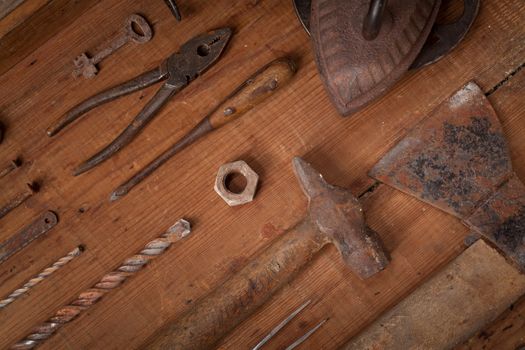 Top view on a collection of old tools on wooden background: pliers, screwdrivers, hammer, axe . Repairing, craftsmanship and handwork concept, flat lay.