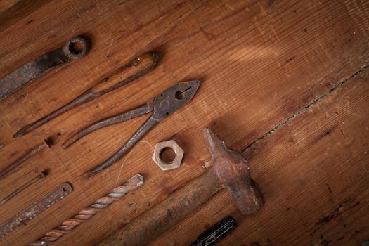 Top view on a collection of old tools on wooden background: pliers, screwdrivers, hammer, axe . Repairing, craftsmanship and handwork concept, flat lay.