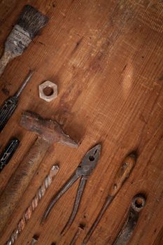 Top view on a collection of old tools on wooden background: pliers, screwdrivers, hammer. Repairing, craftsmanship and handwork concept, flat lay.