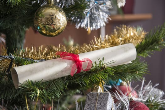 paper scroll, wishlist rolled up on christmas tree. Beautiful close up holiday photo.