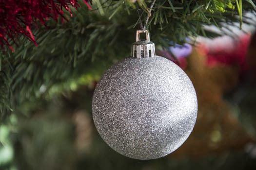 silver bauble ornament hanging on christmas tree. Beautiful close up holiday photo. 
