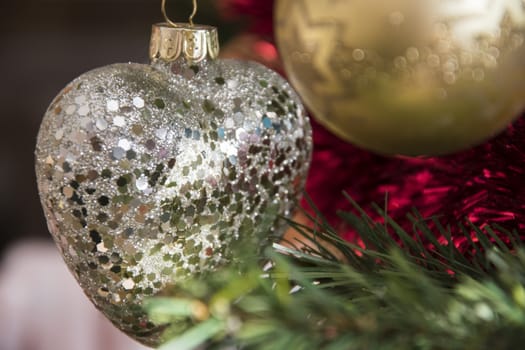 Heart ornament hanging on christmas tree. Beautiful close up holiday photo. 
