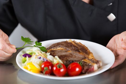 Chef finishing her plate and almost ready to serve at the table