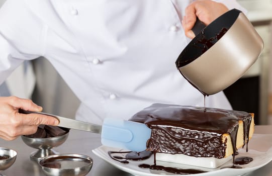 Pastry chef in the kitchen decorating a cake of chocolate