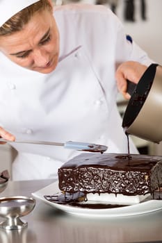 Pastry chef in the kitchen decorating a cake of chocolate