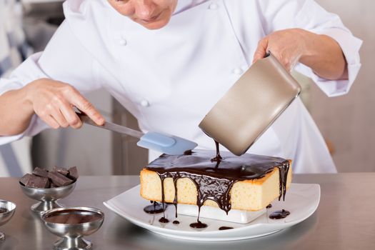 Pastry chef in the kitchen decorating a cake of chocolate