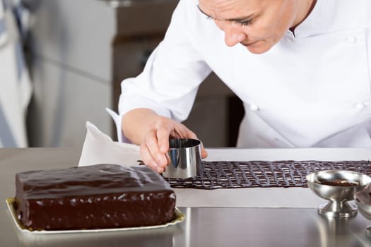 Pastry chef in the kitchen decorating a cake of chocolate