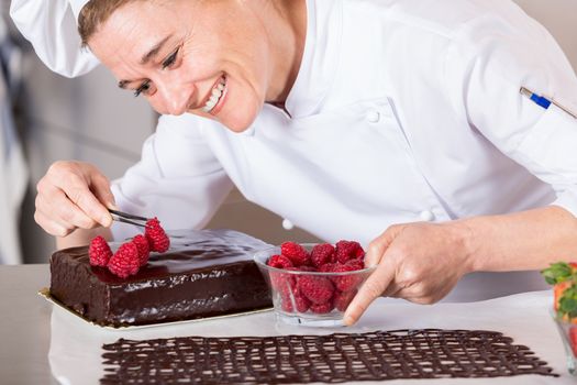 Pastry chef in the kitchen decorating a cake of chocolate