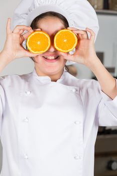 Teen girl in the kitchen playing with two oranges