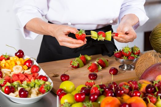 Chef preparing a variety of mixed fruit skewers