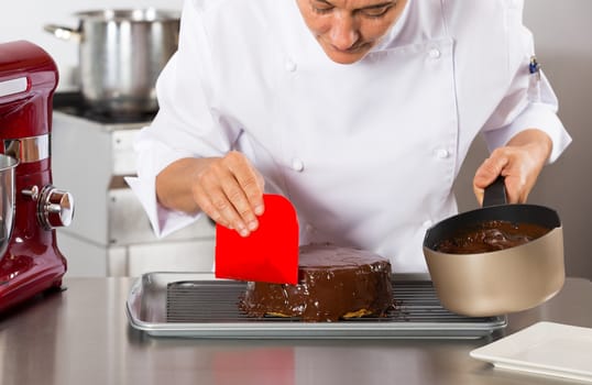 Pastry chef in the kitchen decorating a cake of chocolate