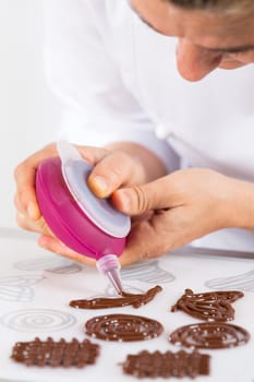 Chef making figures with chocolate to decorate a cake