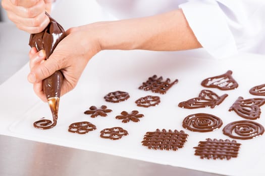Chef making figures with chocolate to decorate a cake