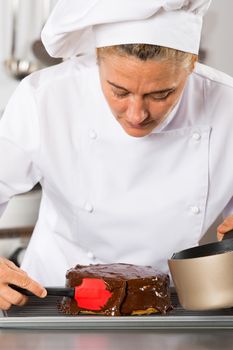 Pastry chef in the kitchen decorating a cake of chocolate