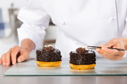 Chef decorating finishing two cakes of chocolate and cream