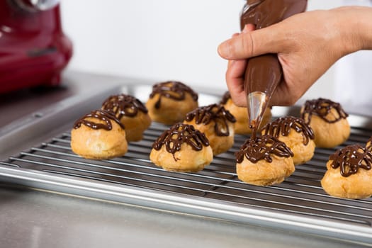 Chef decorating a chocolate profiteroles filled with cream