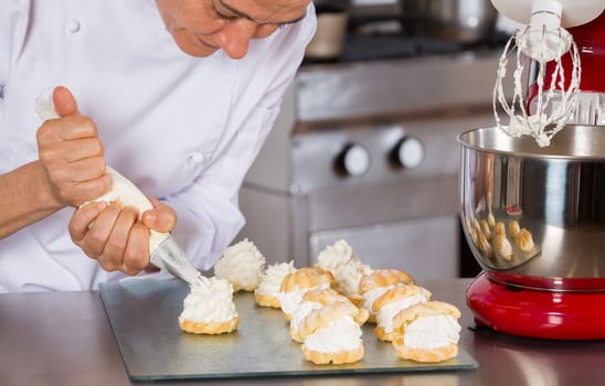Pastry chef decorating with a sleeve profiteroles