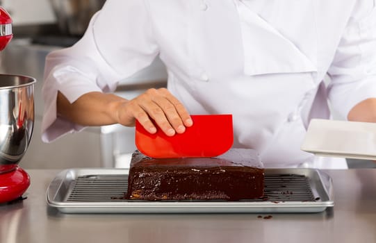 Pastry chef in the kitchen decorating a cake of chocolate
