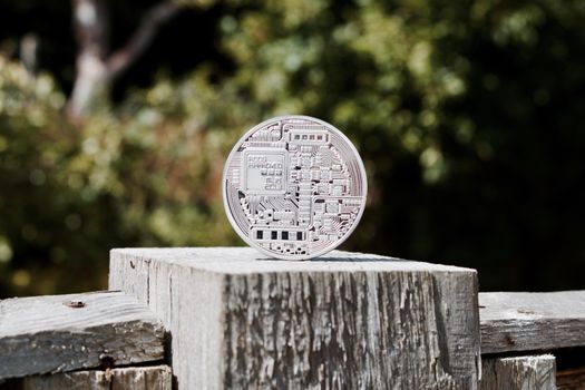 Digital currency physical silver bitcoin coin on the wooden fence in the garden.