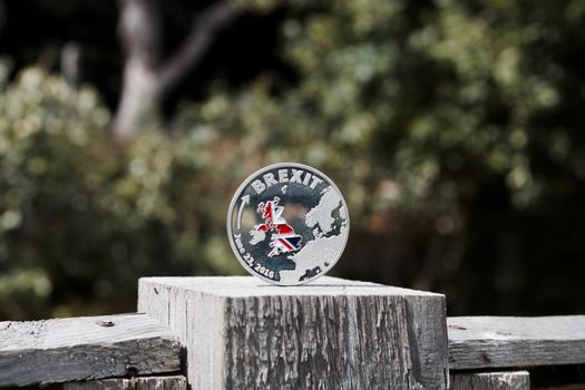 Europe leaving. Silver brexit coin with british map on the wooden fence in garden.