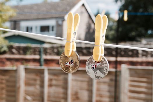 Two plated gold and silver brexit coins on the white laundry line. British map. Europe leaving.