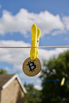 Digital currency physical gold bitcoin coin on white line. Yellow clips.