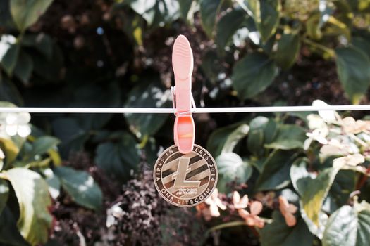 Digital currency physical gold litecoin coin on the white line with laundry clips.