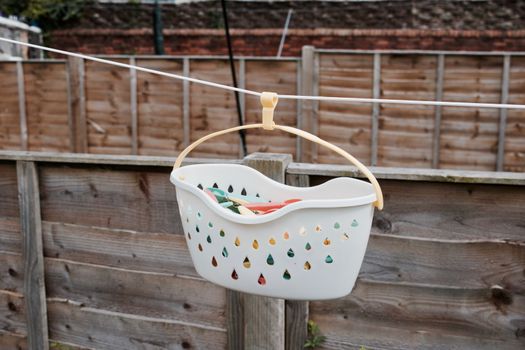 White basket with a colorful laundry clips in the garden on white line.