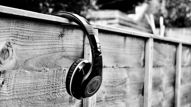 Black dirty headphones on the wall in garden. Black and white concept.