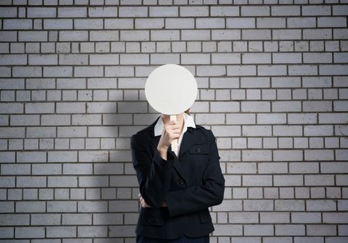 Businesswoman hiding her face behind round banner with smiley