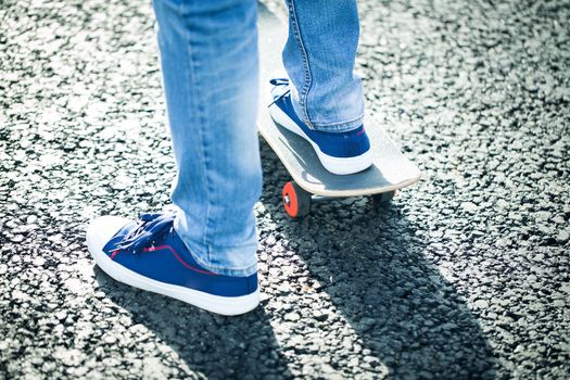 male feet in blue trainers and skateboard close up.