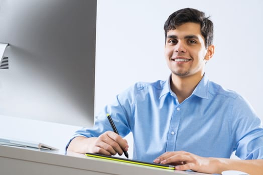 Young graphic designer sitting at desk and working