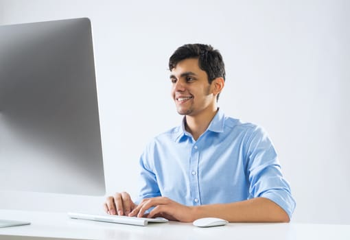 Young man sitting at desk and working on computer