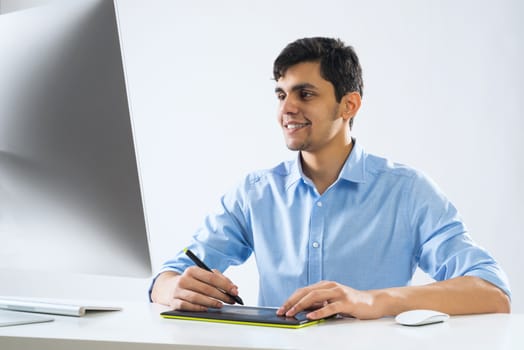 Young graphic designer sitting at desk and working