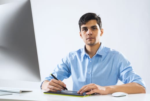 Young graphic designer sitting at desk and working