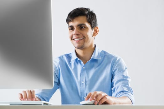 Young man sitting at desk and working on computer