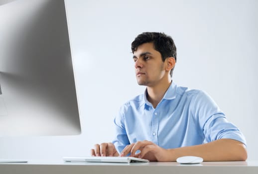 Young man sitting at desk and working on computer