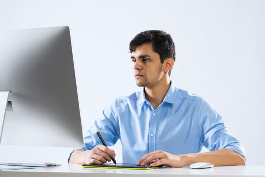Young graphic designer sitting at desk and working